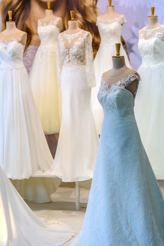 A display of elegant white wedding dresses on mannequins showcasing lace and silk designs.