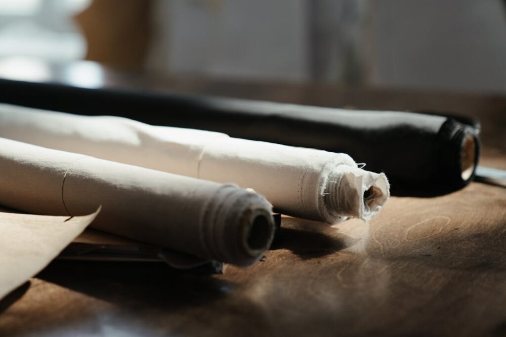 Detailed view of fabric rolls on a wooden table in an artisan workshop, capturing texture and craftsmanship.